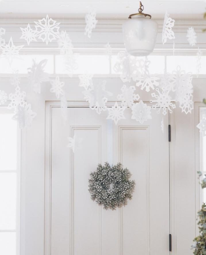 Развешивание снежинок из бумаги и серебряный венок как новогоднее украшение для входа